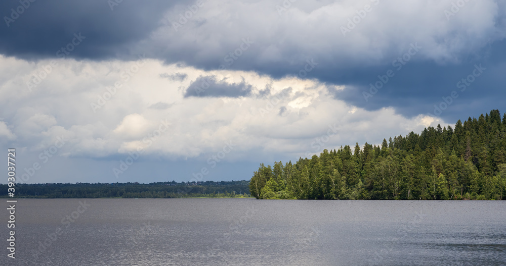 Picturesque summer lake landscape. The forest on the shore of the lake. Beautiful clouds in the sky.