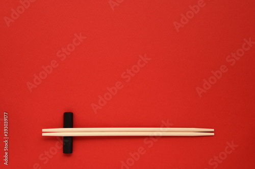 Disposable wooden chopsticks on red background. 