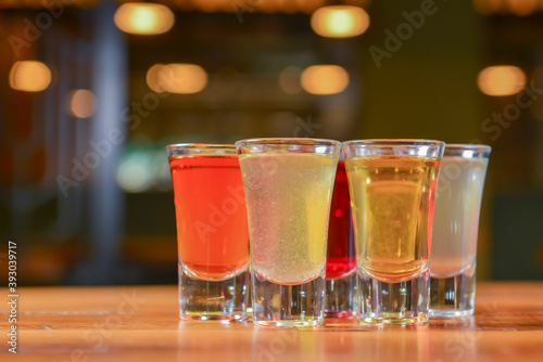 Tincture alcoholic in small shot glasses. Natural fruit alcohol drinks, shots served on a wooden table.