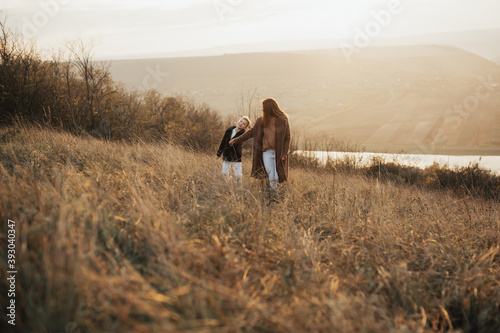 Mother and child boy holding each other hands and walking on the autumn hill. Family and motherhood concept.  © eduard