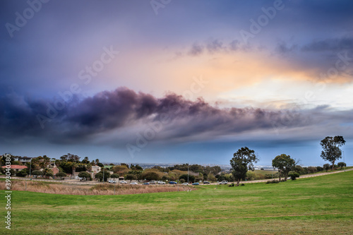 View of  Table Mountain covered in clouds at sunset with a lake and green lawn in foreground, Cape Town, South Africa