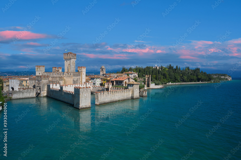 Scaligero Castle in Sirmione, sunrise, pink clouds . Aerial view on Sirmione sul Garda. Italy, Lombardy.Tourist destination in Lombardy region of Italy. Aerial photography with drone.