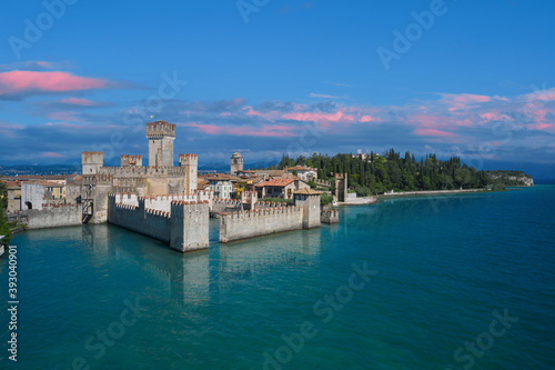 Fototapeta Naklejka Na Ścianę i Meble -  Scaligero Castle in Sirmione, sunrise, pink clouds . Aerial view on Sirmione sul Garda. Italy, Lombardy.Tourist destination in Lombardy region of Italy. Aerial photography with drone.