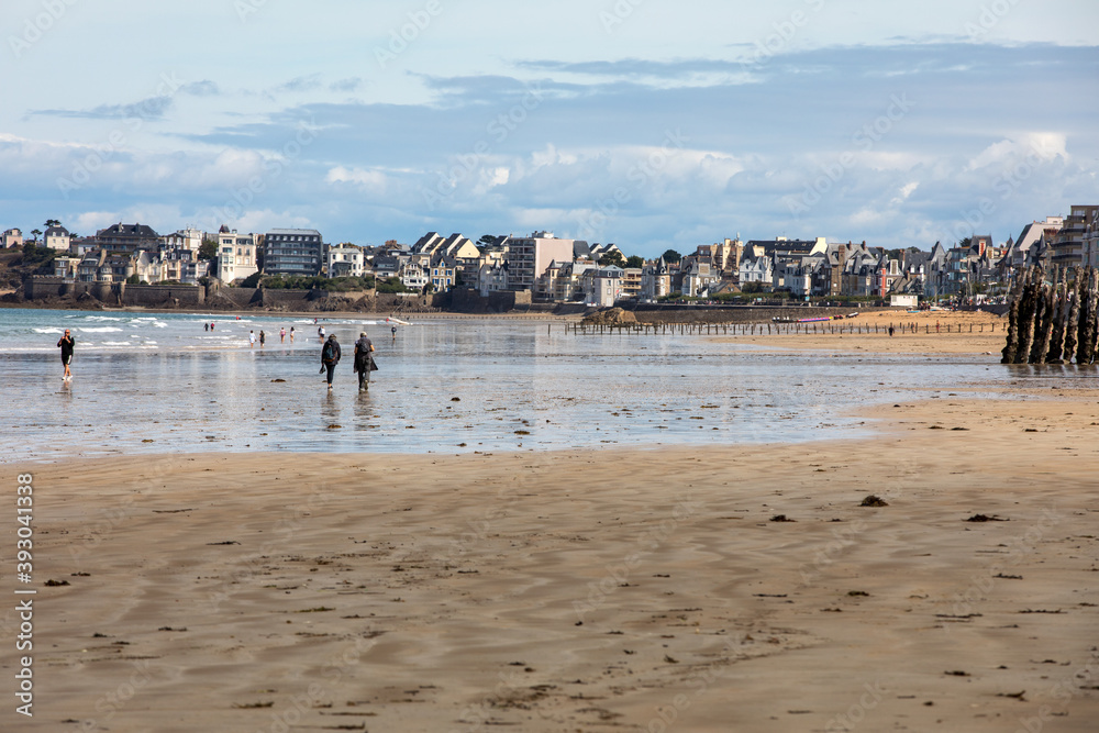  People are walking on a sunny day along the beach in  in Saint-Malo, Brittany, France