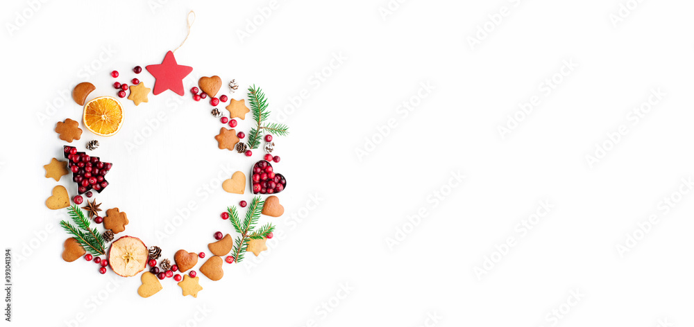 Christmas Decorative wreath made of festive elements, oranges, cranberries and gingerbread cookies on white background.