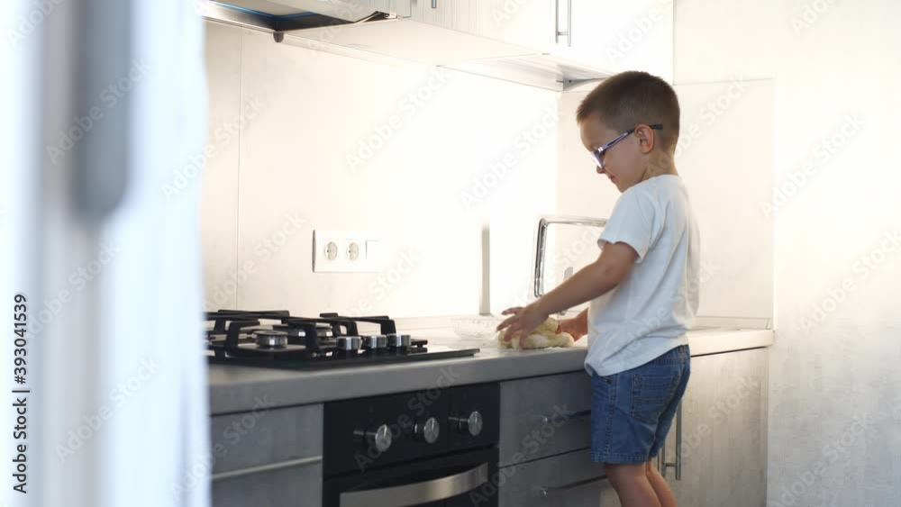 Little boy makes dough in the kitchen. Little boy makes dough in the kitchen.
