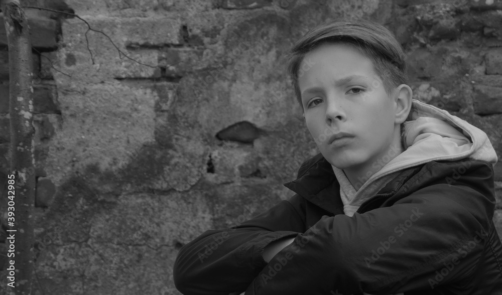 Beautiful boy with a serious look on the background of a red brick wall.A boy with a smart look looks at the camera. Beautiful boy with a serious look on the background of a red brick wall.A boy with a smart look looks at the camera.