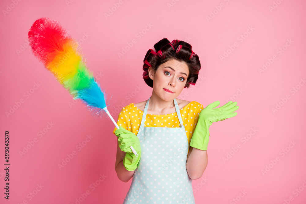 Unsure maid hold soft duster wear yellow dotted t-shirt green lifestyle latex rubber gloves isolated pastel color background Unsure maid hold soft duster wear yellow dotted t-shirt green lifestyle latex rubber gloves isolated pastel color background