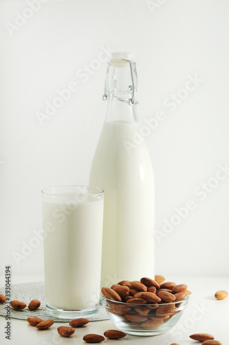 A glass with almond milk and the bowl with almonds