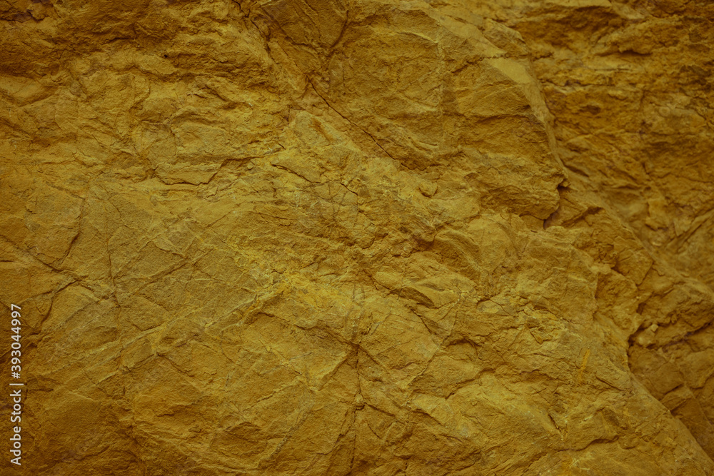 Toned rock texture. Orange stone background. Combination of mustard color and rough rock texture.