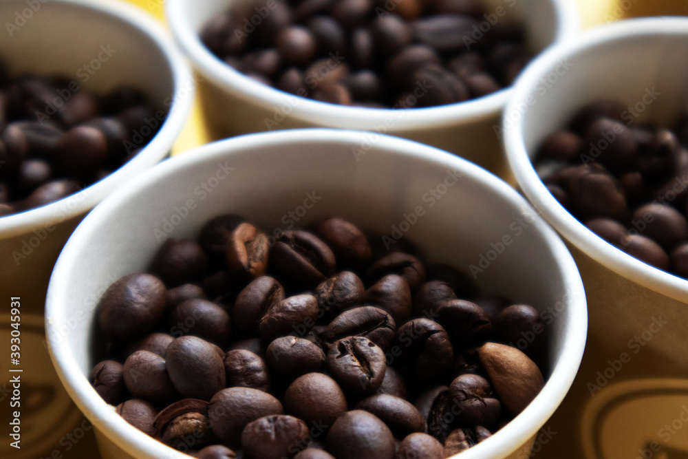 The tops of few cardboard cups full of roasted coffee beans The tops of few cardboard cups full of roasted coffee beans
