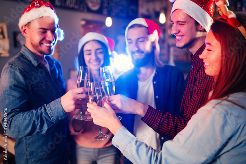Happy group of young friends touching the glasses with each other. Friends celebrating winter holidays in luxury nightclub together. Relax, clinking wineglass, surprise.
