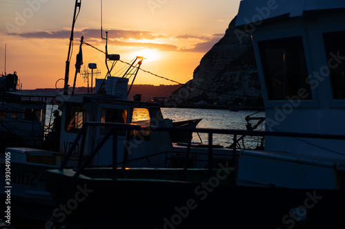 Fototapeta Naklejka Na Ścianę i Meble -  Kavarna, Bulgaria - September 2016: Sunset with a view through a fishing trawler lying in the port