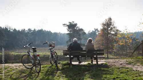 couple on bench resting from bicycle trip in autumn forest near Zeist in holland