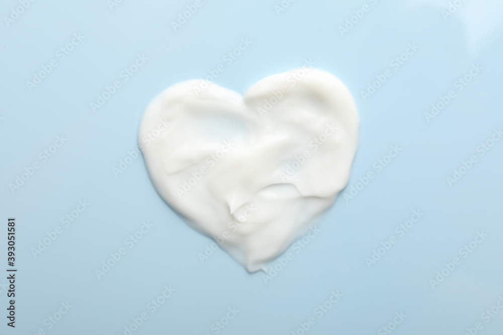 Heart made of cosmetic cream on blue background