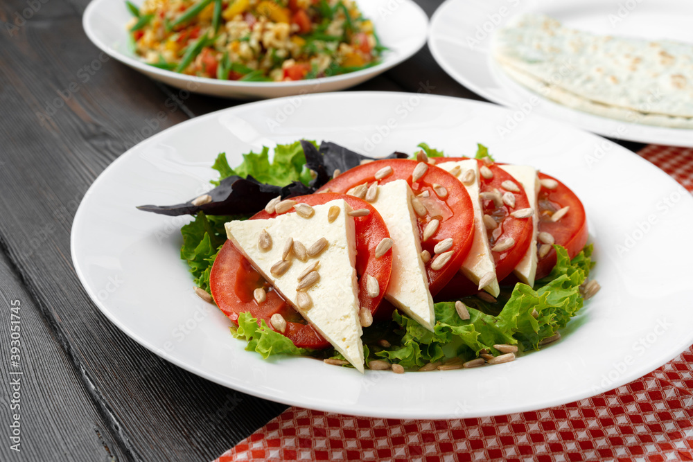 Salad with fresh tomatoes and brined cheese, sunflower seeds on top Salad with fresh tomatoes and brined cheese, sunflower seeds on top