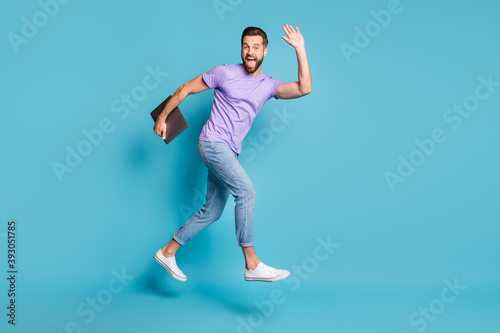 Full length body size photo of jumping student with computer waving greeting giving high-five isolated on bright blue color background photo