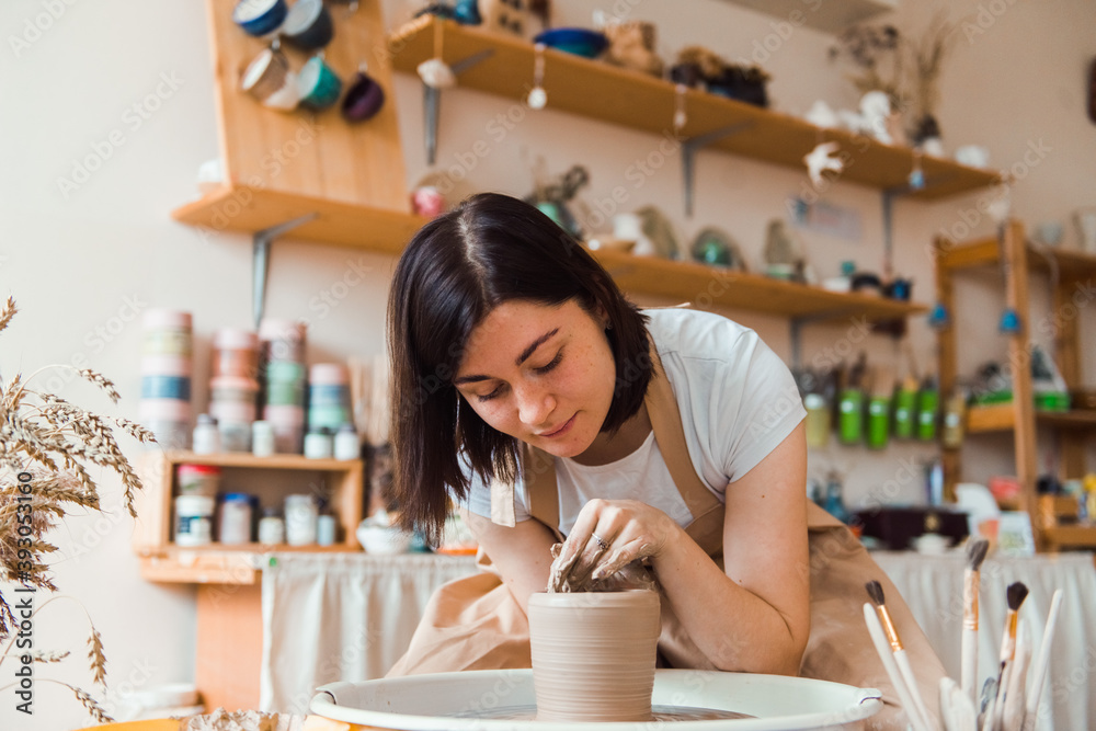 girl works in a ceramics workshop behind a potter's wheel