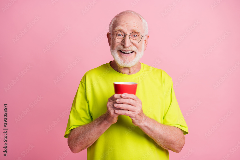 Portrait of funky optimistic pensioner hold cup wear spectacles lime color t-shirt isolated on pastel pink color background Portrait of funky optimistic pensioner hold cup wear spectacles lime color t-shirt isolated on pastel pink color background