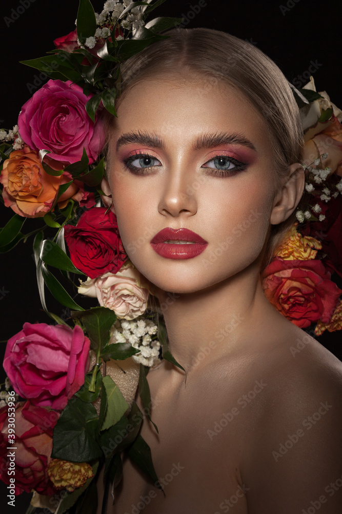 Portrait of a beautiful young girl with stylish make-up decorated with beautiful live roses