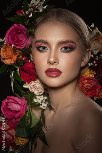Portrait of a beautiful young girl with stylish make-up decorated with beautiful live roses