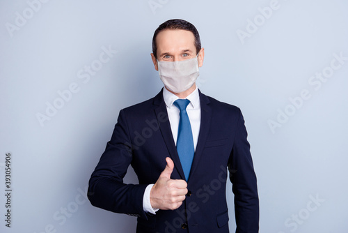 Photo portrait businessman showing thumb up wearing white face mask isolated on grey colored background