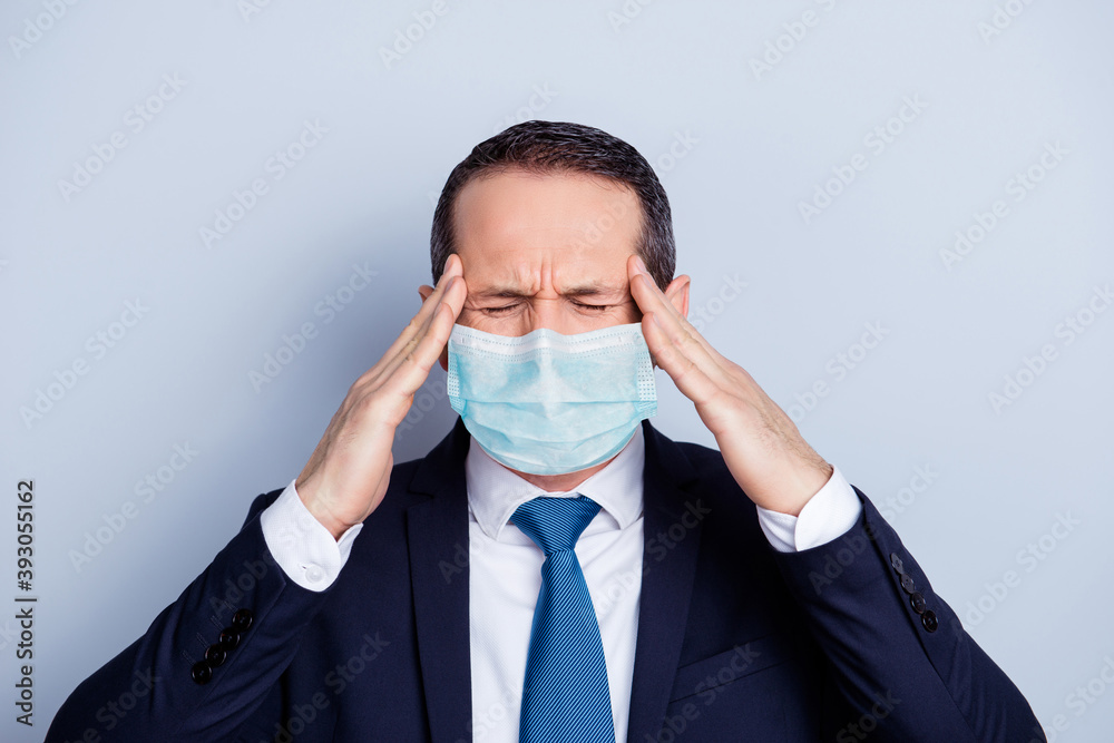 Photo portrait of businessman with headache touching temples with hands wearing blue face mask isolated on white colored background Photo portrait of businessman with headache touching temples with hands wearing blue face mask isolated on white colored background