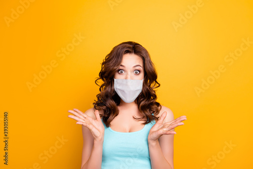 Portrait of scared mad girl wearing white face mask isolated on yellow background