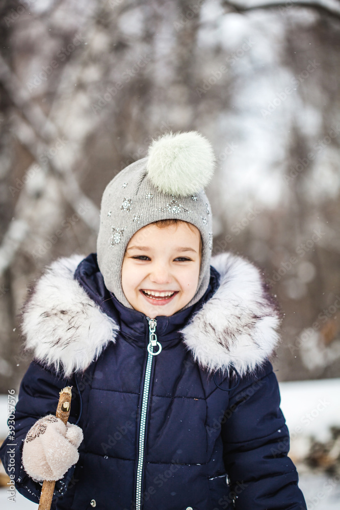 Girl child walking in the winter forest in a blue jacket and gray hat, snow and snowflakes, frosty air, baby's smile Girl child walking in the winter forest in a blue jacket and gray hat, snow and snowflakes, frosty air, baby's smile