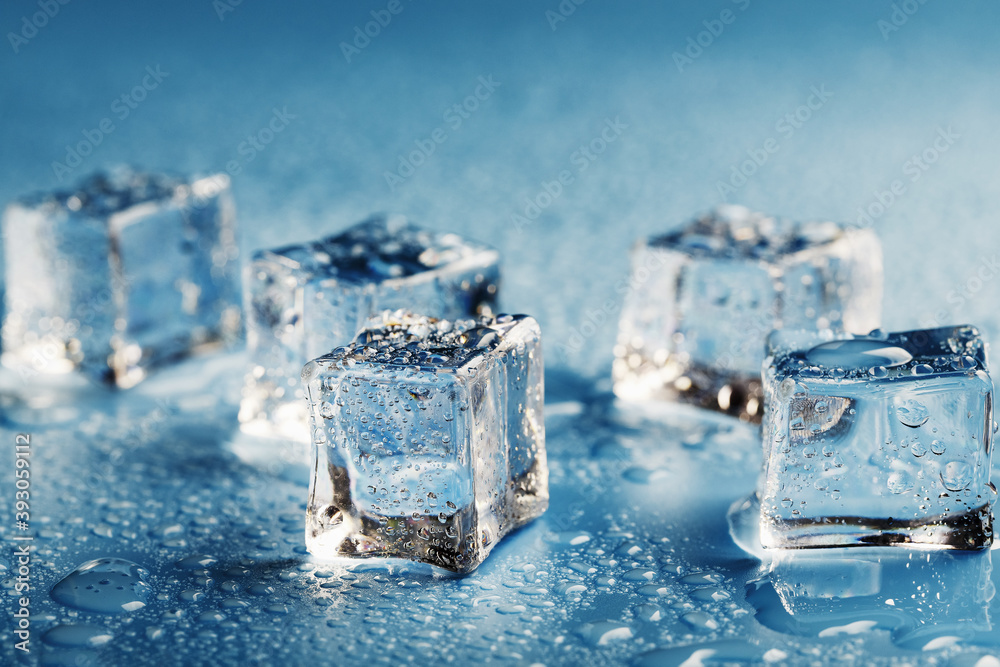 Close-up ice cubes with melt water drops scattered on a blue background. Close-up ice cubes with melt water drops scattered on a blue background.