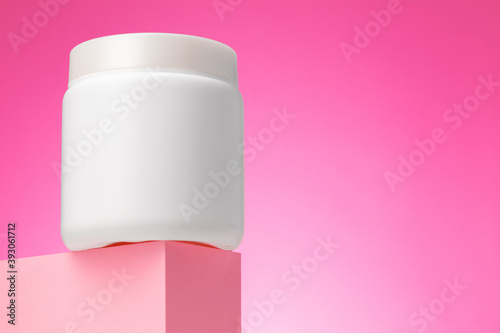 Blank white cosmetic container against pink background