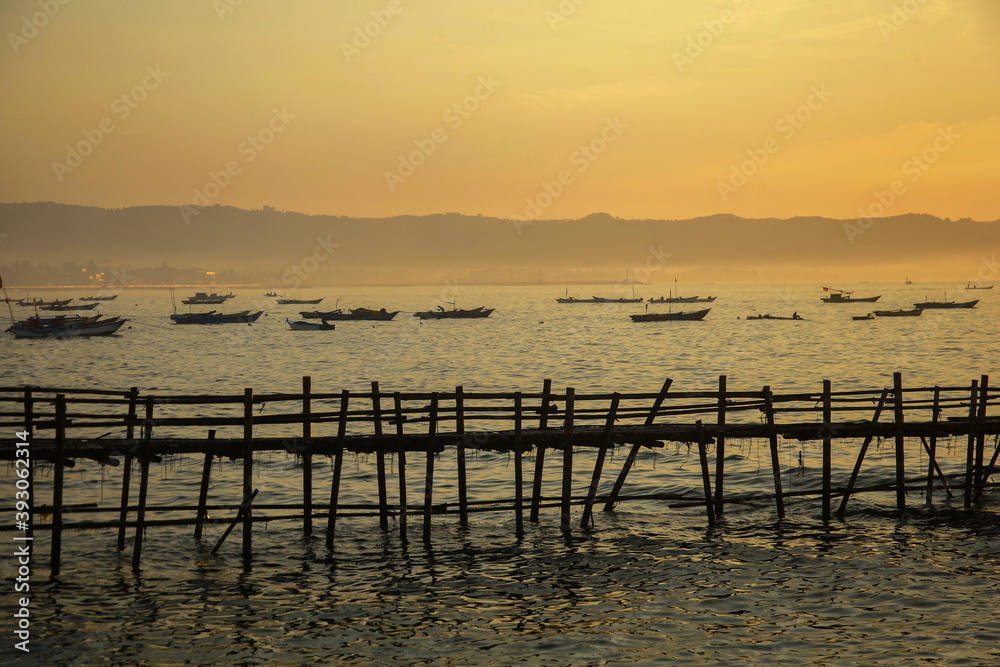 Fototapeta premium Sunrise view from sea with beautiful twilight sky, fishing boats preparing the trap with mountain in background.