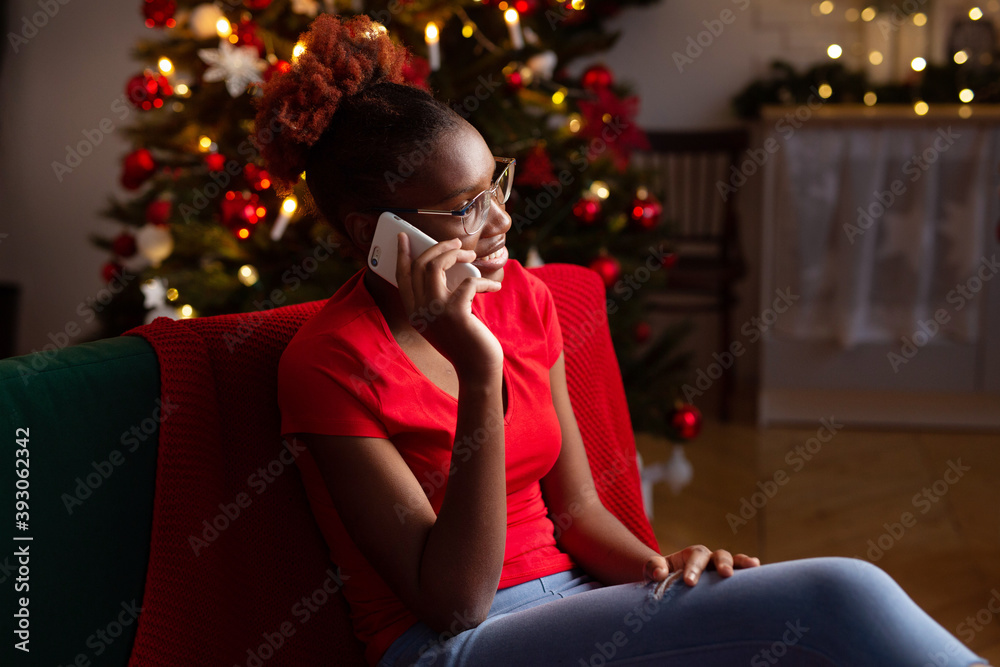 beautiful young african female sitting with mobile phone on the sofa