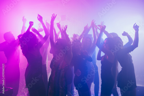 Photo of people charming girls dance raise hands party in neon light wear stylish outfit glossy dress modern club indoors