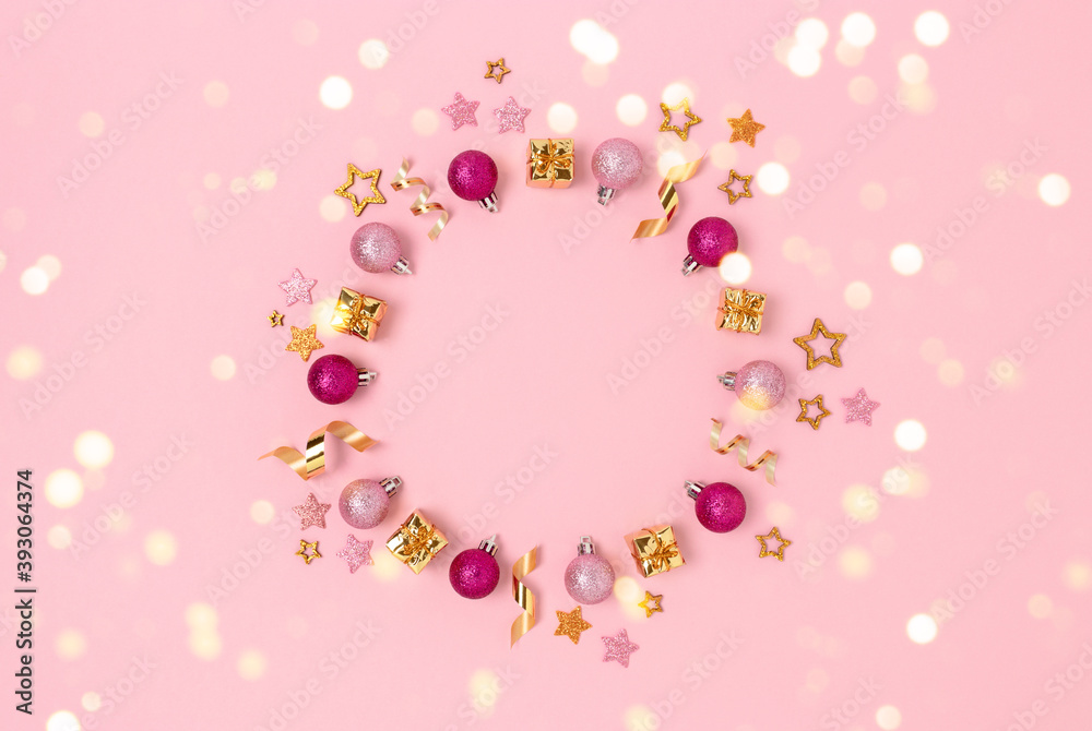 Wreath made of Christmas decorations and gold confetti. Minimalist festive frame on a pink pastel background. Wreath made of Christmas decorations and gold confetti. Minimalist festive frame on a pink pastel background.