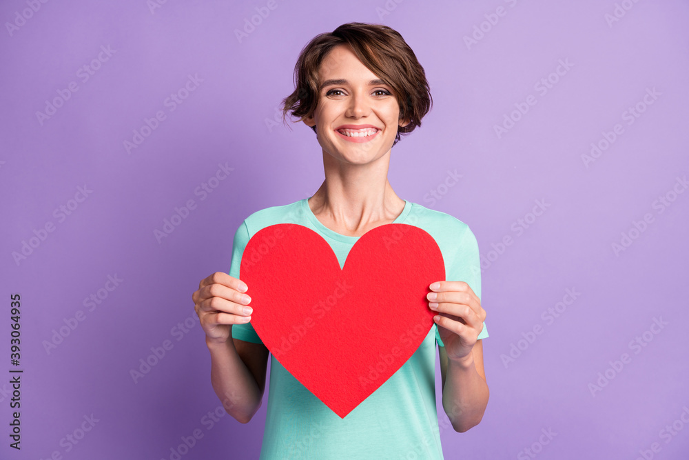 Photo of lovely young woman dressed casual turquoise clothes holding big red heart isolated violet color background Photo of lovely young woman dressed casual turquoise clothes holding big red heart isolated violet color background