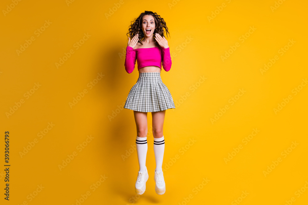 Photo portrait of girl jumping screaming hands near face wearing fuchsia crop-top checkered skirt knee-high socks white sneakers isolated on bright yellow colored background Photo portrait of girl jumping screaming hands near face wearing fuchsia crop-top checkered skirt knee-high socks white sneakers isolated on bright yellow colored background