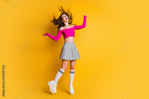 Full body photo of pretty charming overjoyed lady close eyes throw curly hairstyle wear pink cropped top short plaid skirt white long socks shoes isolated yellow color background