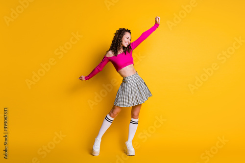 Full length photo of attractive charming crazy glad lucky wavy lady raise spread arms wear pink cropped top mini plaid skirt white socks shoes isolated yellow color background