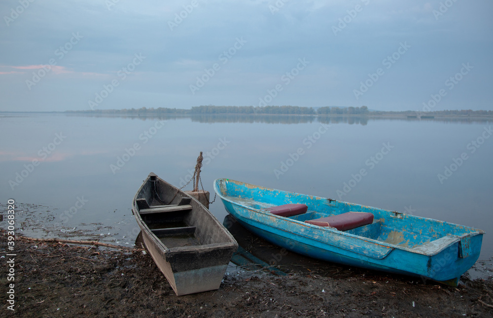 Foggy dawn over the lake. Lonely boats on the shore.