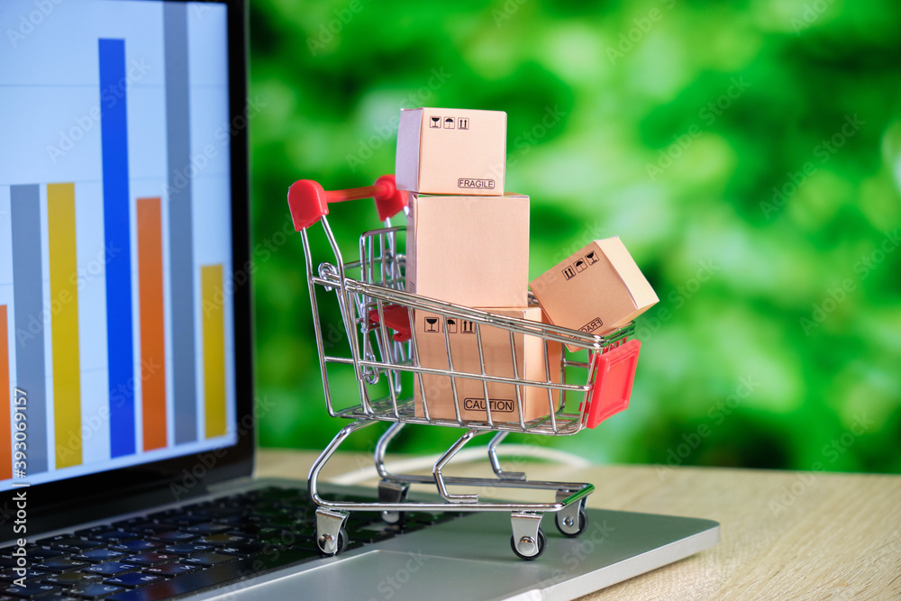 The concept of purchasing goods online. Store cart with boxes on a laptop