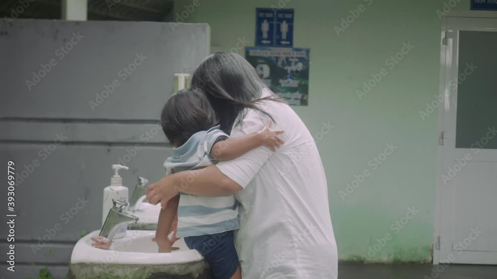 Handheld medium wide shot of an Asian mother and son washing their hands outside. Handheld medium wide shot of an Asian mother and son washing their hands outside.