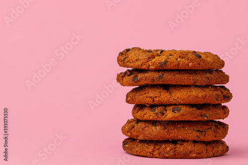 Stacked chocolate chip cookies against pink background
