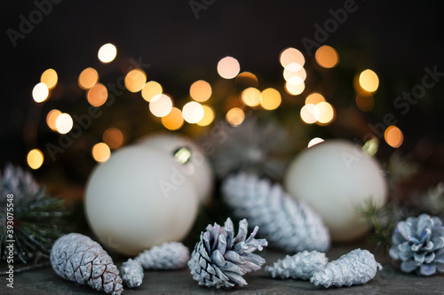 Christmas cones painted white on a gray background in the background Christmas balls and lights in bokeh 