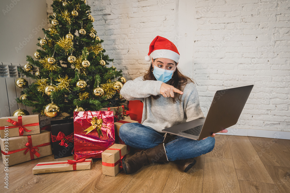 Happy woman in lockdown with face mask on video call celebrating virtual christmas with family Happy woman in lockdown with face mask on video call celebrating virtual christmas with family
