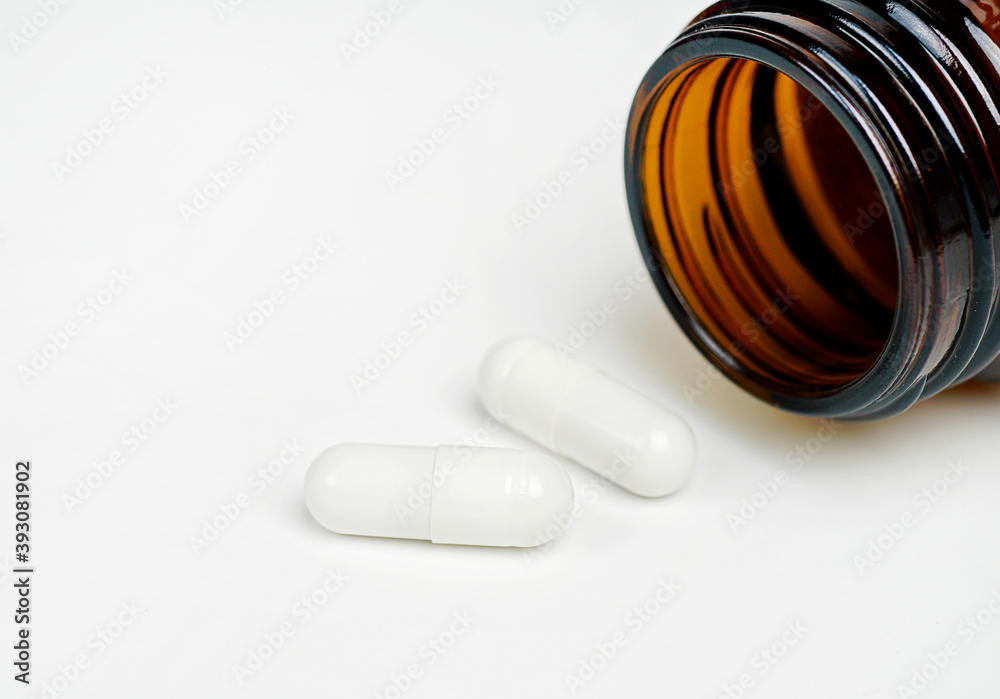 Glass bottles with pills scattered nearby on a white background. Glass bottles with pills scattered nearby on a white background.