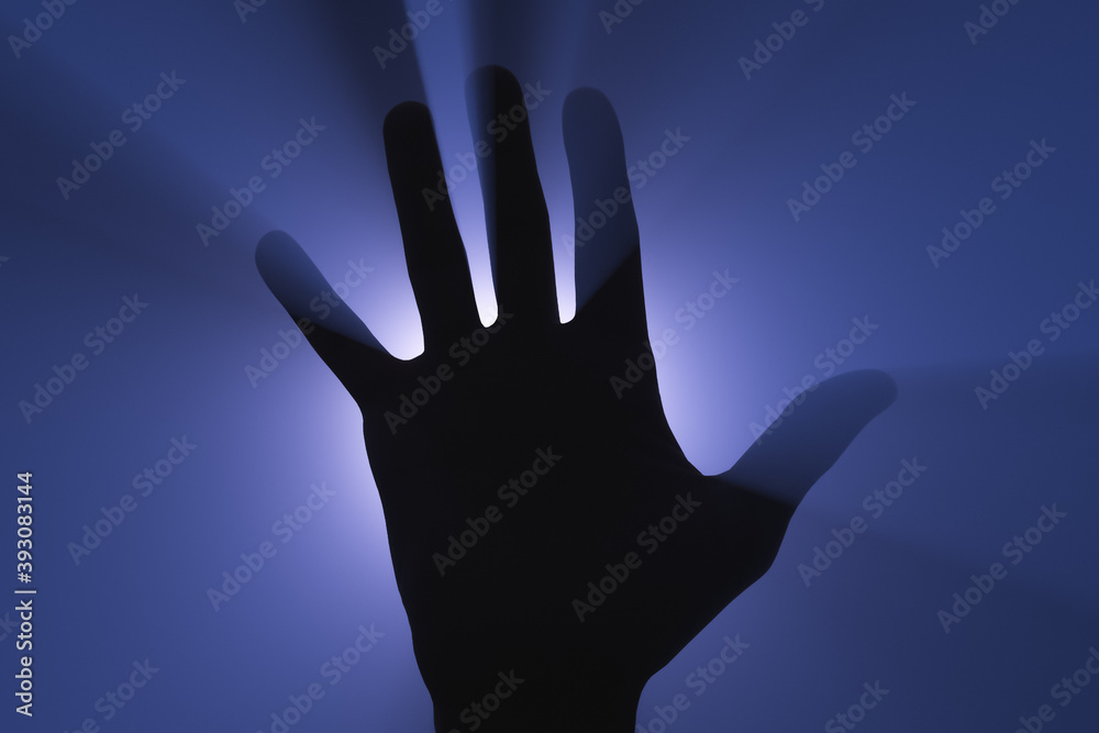 Human hand silhouette in the light of a spotlight.