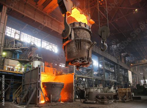 A stream of hot metal pours into the ladle. Electric arc furnace shop EAF. Metallurgy.