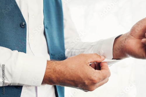 The man fastens the buttons on the shirt. Morning of the groom. Hands of wedding groom buttoning up his white shirt.