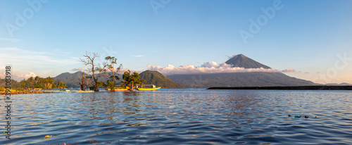 View over the tropical ocean in indonesia with boats and vulcano island in background